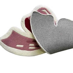 May include: Two heart-shaped rugs. One rug is pink with white and red accents. The other rug is gray. The rugs are made of a soft, textured material. The rugs are designed to be decorative.
