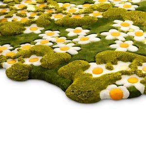 May include: A whimsical rug featuring a field of white daisies with yellow centers and green foliage. The rug has a textured, three-dimensional design, creating a playful and inviting aesthetic. The rug's shape is irregular, adding to its unique charm.