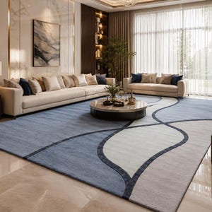 May include: A large rectangular area rug featuring a geometric pattern of overlapping curved lines in shades of blue, light gray, and dark navy. The rug has a low-pile texture and covers a significant portion of the floor in a living room space.