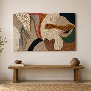 May include: A rectangular wall hanging featuring a tufted fiber art design with varied textures and colors including cream, beige, navy blue, forest green, terracotta, and mustard yellow. The piece incorporates raised yarn loops and tufted sections.