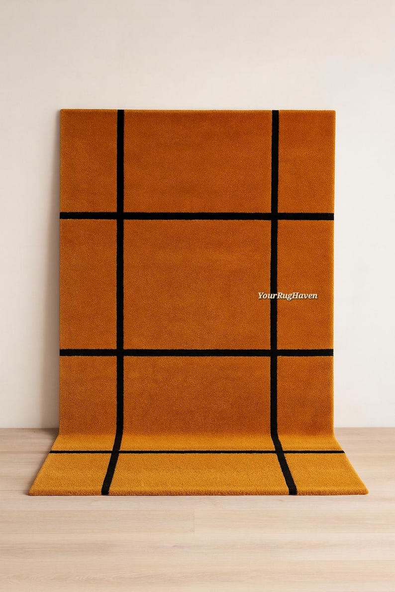 May include: Mustard-colored rectangular rug with a black grid pattern. The rug is made of a soft material and has a modern design. The text "YourRugHaven" is visible on the rug.