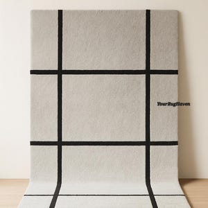 May include: Sage gray rectangular rug with a black grid pattern. The rug is displayed on a light wood floor, with the top portion against a neutral wall. The text "YourRugHaven" and "Sage Gray" are visible.