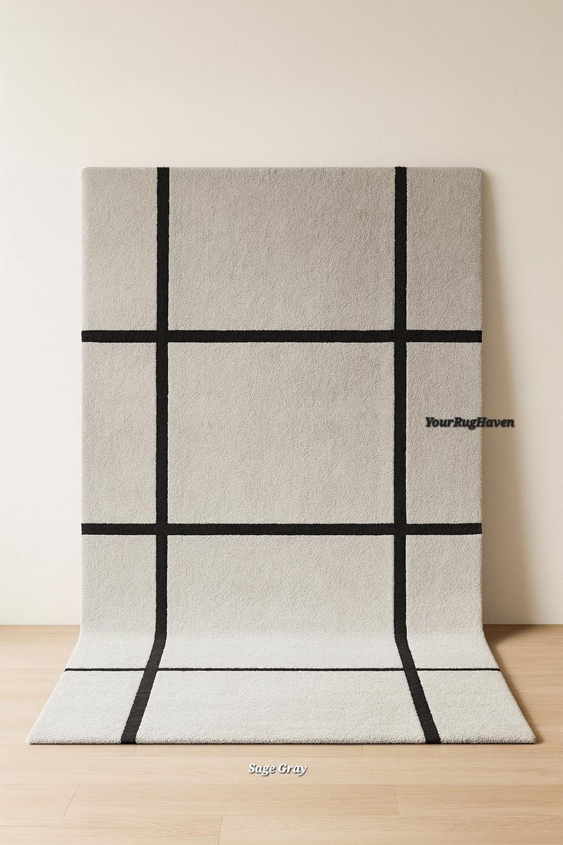 May include: Sage gray rectangular rug with a black grid pattern. The rug is displayed on a light wood floor, with the top portion against a neutral wall. The text "YourRugHaven" and "Sage Gray" are visible.