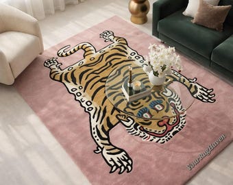 May include: A pink rug featuring a tiger design in tan, black, and white. The rug is rectangular, displaying the tiger's full body with outstretched head and paws. A glass coffee table rests on the rug. The rug is a statement piece.