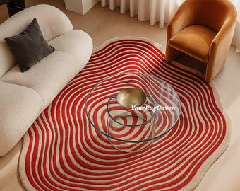May include: A red and beige area rug with a wavy, concentric design. The rug is placed in a living room setting with a glass coffee table, a white sofa, and an orange armchair. The rug's pattern resembles ripples.