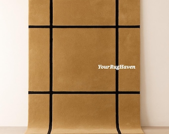 May include: A rectangular, tan-colored rug with a grid pattern of thick, black lines. The rug is displayed on a light wood floor, with the top portion against a white wall. The text "YourRugHaven" is visible on the rug.