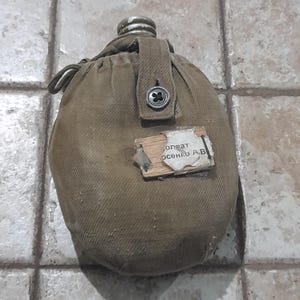 May include: A white ceramic mug with a black handle and the text "But First, Coffee" in a handwritten style. The mug is on a white surface. The mug is likely for hot beverages.