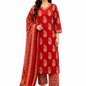 May include: A red Indian salwar kameez suit with a paisley pattern. The outfit includes a tunic, matching trousers, and a patterned scarf. The ensemble is decorated with gold accents and is suitable for festive occasions.