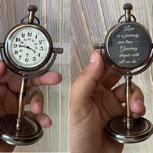 May include: A vintage-style desk clock with a round face and a decorative base. The clock face displays Roman numerals and hands. The clock is supported by a brass-colored stand. The clock's face is 3 inches in diameter.