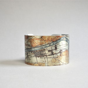 May include: A silver metal cuff bracelet with a vintage map design featuring the city of Huntington, West Virginia. The map shows the Ohio River and surrounding areas.