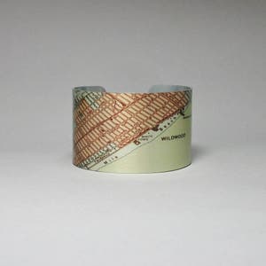 May include: A silver cuff bracelet with a vintage map of Wildwood, New Jersey printed on it. The map shows the location of the White Dome and the beach.