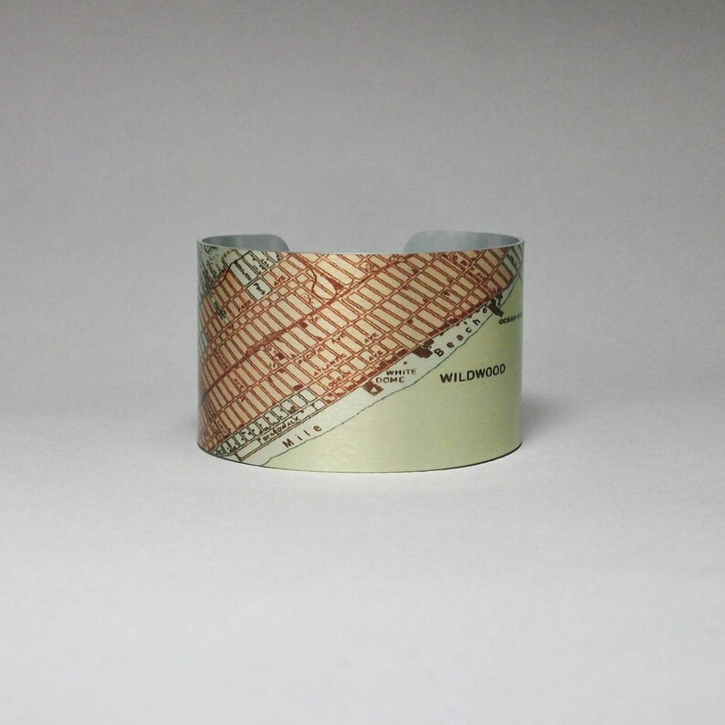 May include: A silver cuff bracelet with a vintage map of Wildwood, New Jersey printed on it. The map shows the location of the White Dome and the beach.