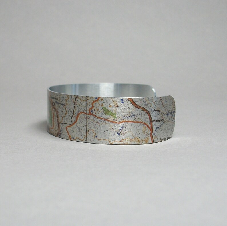 May include: A silver metal bracelet with a map design. The map features a variety of geographical features, including roads, rivers, and towns. The bracelet is a unique and stylish way to show your love for travel and adventure.
