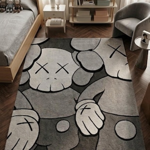 K&ouml;nnte beinhalten: Ein rechteckiger Teppich mit einem gro&szlig;fl&auml;chigen Grafikdruck von zwei Zeichentrickfiguren mit X-f&ouml;rmigen Augen und behandschuhten H&auml;nden. Das Design verwendet eine monochrome Farbpalette aus Hellgrau, Dunkelgrau und Schwarz mit kr&auml;ftigen Konturen.