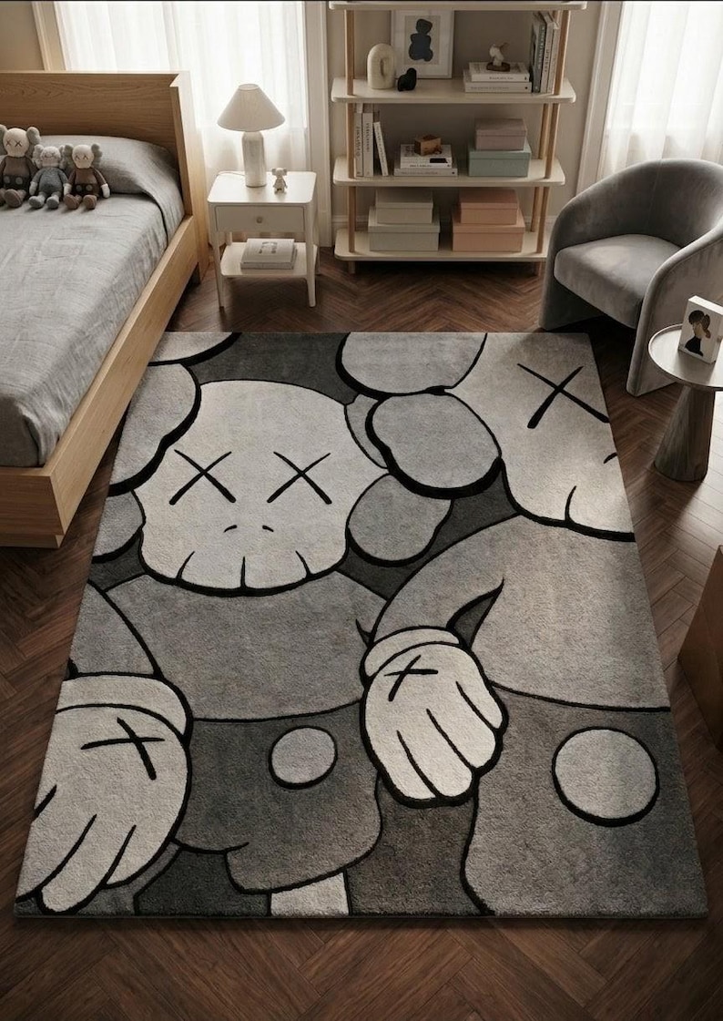 K&ouml;nnte beinhalten: Ein rechteckiger Teppich mit einem gro&szlig;fl&auml;chigen Grafikdruck von zwei Zeichentrickfiguren mit X-f&ouml;rmigen Augen und behandschuhten H&auml;nden. Das Design verwendet eine monochrome Farbpalette aus Hellgrau, Dunkelgrau und Schwarz mit kr&auml;ftigen Konturen.