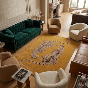 May include: A rectangular area rug featuring a mustard yellow background with two large, mirrored cheetah illustrations in black and tan. The rug is positioned in the center of a room surrounded by a dark green tufted sofa, four textured armchairs, and a brown leather sofa.
