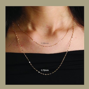 Pu&ograve; includere: Collane a catena color oro, larghe 1,08 mm e 1,72 mm, mostrate su sfondo scuro. Il testo "CHAIN STYLE" &egrave; in alto. Le collane sono mostrate attorno al collo di una persona.