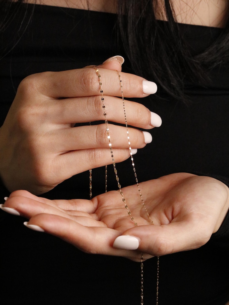 Thin 14k solid gold chain, lightly held in both hands to show its fine craftsmanship, subtle sparkle, and graceful drape, one chain width is slightly thicker 1.72mm, the second chain more dainty 1.05mm thick