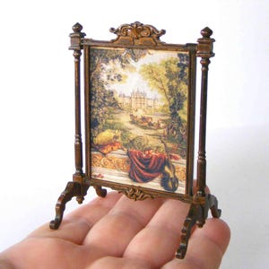 May include: Miniature framed artwork with a landscape scene. The frame is ornate, dark brown, and supported by a stand. The artwork depicts a classical garden scene with a building, trees, and figures. The text "ERZSÉBET BODZÁS Hungarian Miniatures" is at the top.