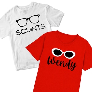 May include: Two t-shirts, one white and one red. The white shirt has a black glasses graphic and the word "SQUINTS". The red shirt has a white-rimmed sunglasses graphic and the name "Wendy" in black script.