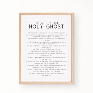May include: A framed print with the text "THE GIFT OF THE HOLY GHOST" in a black font. The print includes a list of related scriptures. The frame is a light brown color.