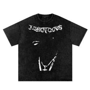 May include: Black t-shirt with the text "A GREAT CHAOS" in a distressed white font. The shirt features a white graphic of a face. The t-shirt has a vintage, worn look.
