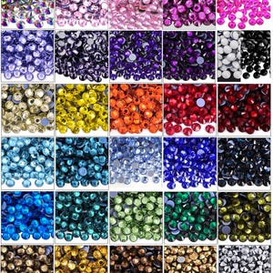 May include: A grid of colorful rhinestones in various shades, including pink, purple, blue, green, yellow, and red. Each color is displayed in a separate square, showcasing the variety of options available for crafts and embellishments.