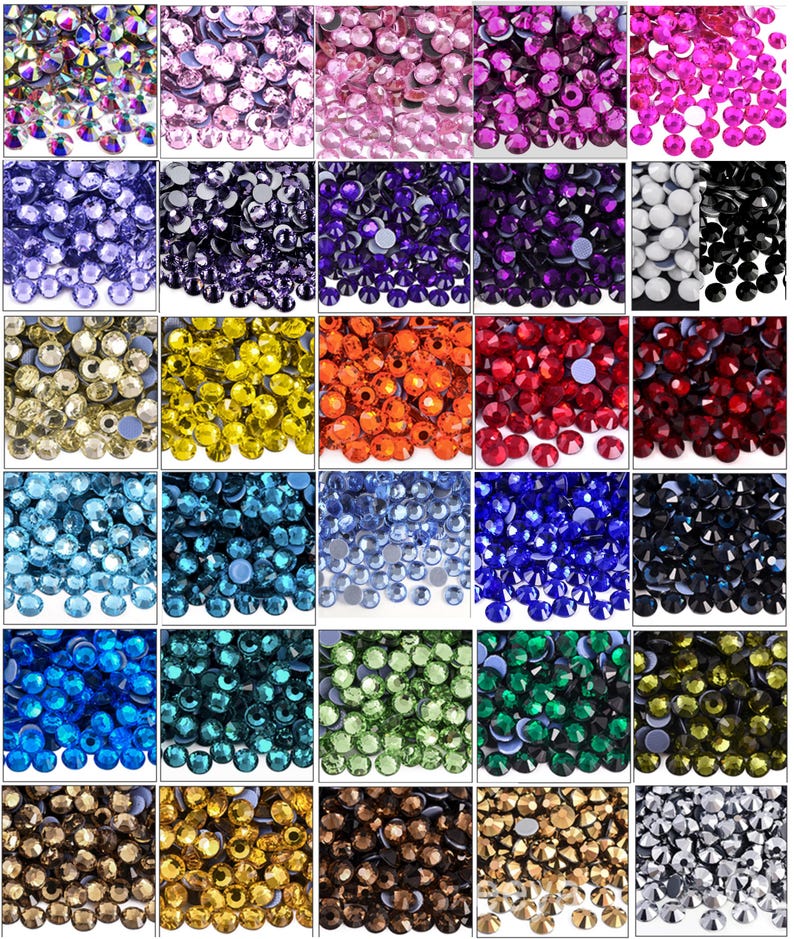May include: A grid of colorful rhinestones in various shades, including pink, purple, blue, green, yellow, and red. Each color is displayed in a separate square, showcasing the variety of options available for crafts and embellishments.