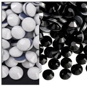May include: A split image showcasing two distinct piles of craft supplies. On the left, a collection of white, rounded rhinestones with a flat back and a blue backing. On the right, a pile of black, faceted rhinestones.