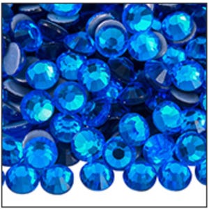 May include: Close-up of a collection of vibrant blue rhinestones. The faceted gems are in various shades of blue, creating a sparkling effect. The rhinestones are round and appear to be scattered, with a few showing their flat backs.