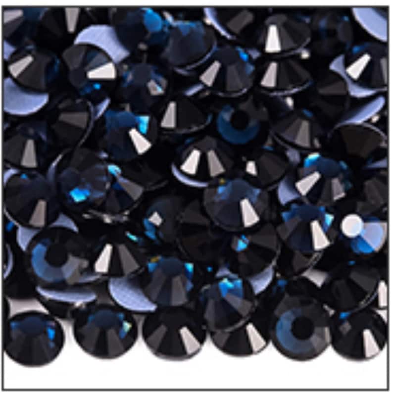 May include: A close-up view of a pile of dark blue rhinestones. Each rhinestone has multiple facets that reflect light, creating a sparkling effect. The rhinestones are round with a flat back.