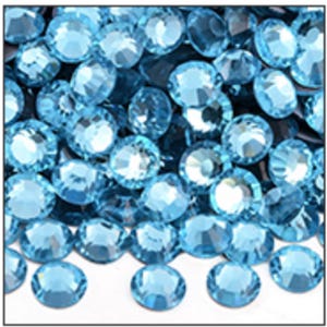 May include: A collection of light blue, faceted rhinestones. The gemstones are round with multiple facets, reflecting light. The gems are scattered, creating a sparkling effect. Ideal for crafting, jewelry making, or adding sparkle to various projects.