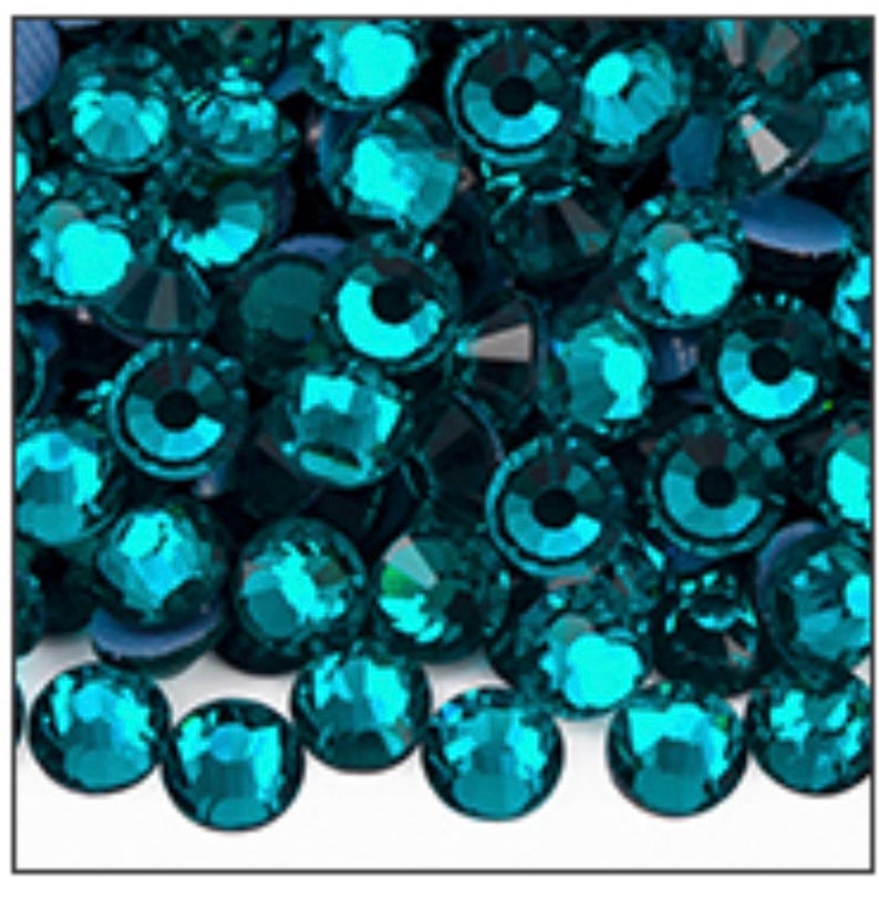 May include: A close-up view showcases a collection of teal-colored rhinestones. Each rhinestone has a faceted surface, reflecting light and creating a sparkling effect. The gems are round with a flat back, suitable for various craft projects.