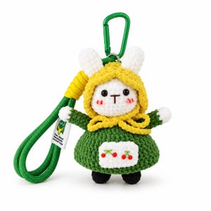 Peut inclure: Un porte-clés lapin en crochet avec une tête blanche, une capuche jaune et une robe verte dotée d'un tablier blanc orné de deux cerises rouges. La figurine a des yeux noirs, un nez marron et des joues roses. Inclut une lanière et un mousqueton verts.