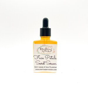 K&ouml;nnte beinhalten: Eine Glasflasche mit Gesichts-Serum und einem schwarzen Tropfer. Das Etikett lautet "Drifting by the Sea Organic Skincare Face Petals Secret Serum Anti-Aging & Skin Plumping WWW.DRIFTINGBYTHESEA.COM"