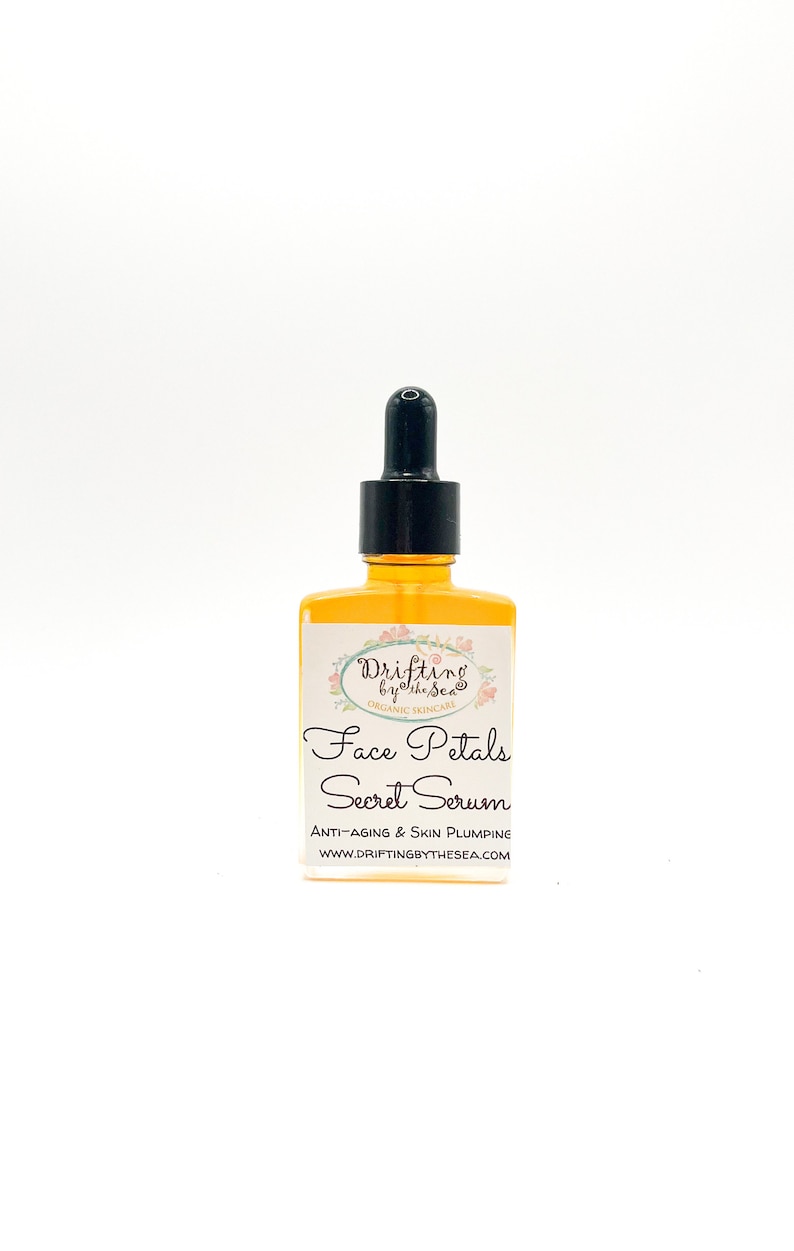 K&ouml;nnte beinhalten: Eine Glasflasche mit Gesichts-Serum und einem schwarzen Tropfer. Das Etikett lautet "Drifting by the Sea Organic Skincare Face Petals Secret Serum Anti-Aging & Skin Plumping WWW.DRIFTINGBYTHESEA.COM"
