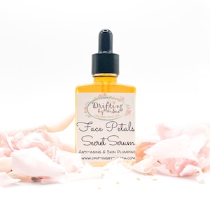 K&ouml;nnte beinhalten: Eine Glasflasche mit Gesichts-Serum und Tropfer. Die Flasche ist mit "Drifting by the Sea" und "Face Petals Secret Serum" beschriftet. Das Etikett tr&auml;gt au&szlig;erdem die Aufschrift "Anti-Aging & Skin Plumping" und "www.driftingbythesea.com". Die Flasche ist von rosa Rosenbl&auml;ttern umgeben.
