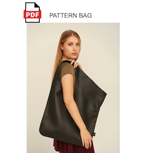 May include: A black tote bag with a minimalist design, held by a person. The bag is approximately 23.6 inches wide and 19.7 inches tall. The image includes the text "PDF PATTERN BAG" and "OneClickToArt".