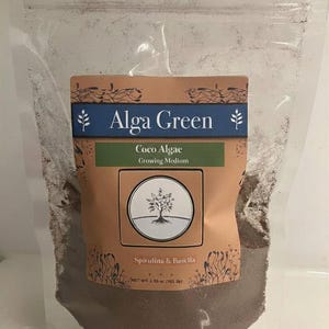 May include: A clear plastic pouch containing dark brown growing medium. The label reads Alga Green, Coco Algae Growing Medium, Spirulina & Basella, with a tree graphic and net weight 3.65 oz (103.5g). The pouch has a resealable top closure.