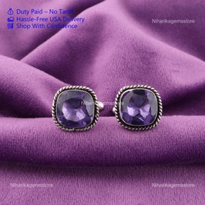 May include: Two square-cut, purple gemstone rings with a silver rope-like border. The rings are displayed on a purple velvet surface. The text "Duty Paid - No Tariff", "Hassle-Free USA Delivery", and "Shop With Confidence" is visible.
