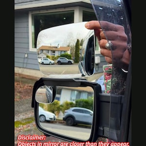 May include: A vehicle side mirror with a rectangular shape, reflecting a residential street scene with houses and cars. The text "Disclaimer: Objects in mirror are closer than they appear" is visible at the bottom.