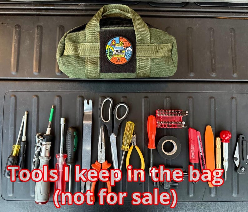 May include: An olive green tool bag with a patch, surrounded by various tools. The tools include screwdrivers, pliers, scissors, and a multi-tool. The text "Tools I keep in the bag (not for sale)" is displayed.