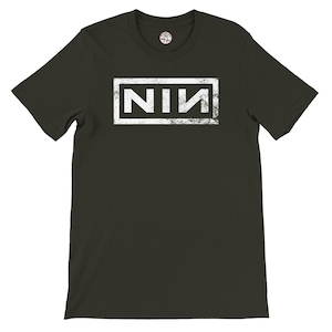 May include: Dark olive green t-shirt featuring the white letters "NIN" within a white rectangular frame. The letters have a distressed, textured look. The shirt has a crew neck and short sleeves.