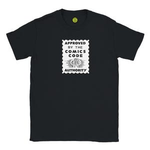 Può includere: T-shirt nera con una grafica bianca a forma di timbro postale con la scritta "APPROVED BY THE COMICS CODE AUTHORITY". La grafica include le lettere "CAD" al centro. Una piccola faccina gialla è visibile vicino allo scollo.