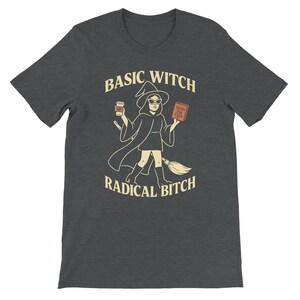 Może przedstawiać: Ciemnoszara koszulka z grafiką czarownicy trzymającej filiżankę kawy i książkę z napisem "Hexes for Exes". Tekst na koszulce brzmi "Basic Witch Radical Bitch."