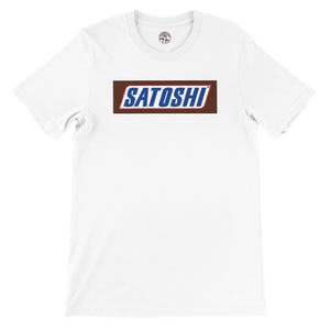 May include: White t-shirt with a rectangular graphic. The graphic features the word "SATOSHI" in blue, stylized to resemble a candy bar logo, set against a brown background. The shirt has a crew neck and short sleeves.