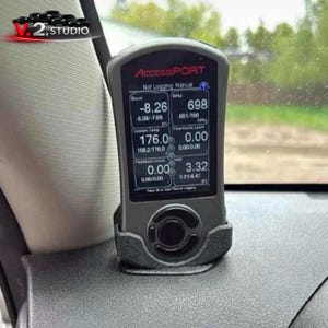 Puede incluir: Un dispositivo Accessport negro que muestra datos del motor en tiempo real, incluyendo la presión de sobrealimentación y las RPM. El dispositivo está montado en un soporte negro. El texto "Accessport" es visible.