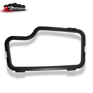 Puede incluir: Una pieza automotriz de fibra de carbono negra con forma rectangular y esquinas redondeadas. La pieza tiene una superficie texturizada y está diseñada para un vehículo. El logotipo "V.2 STUDIO" es visible en la esquina superior izquierda.