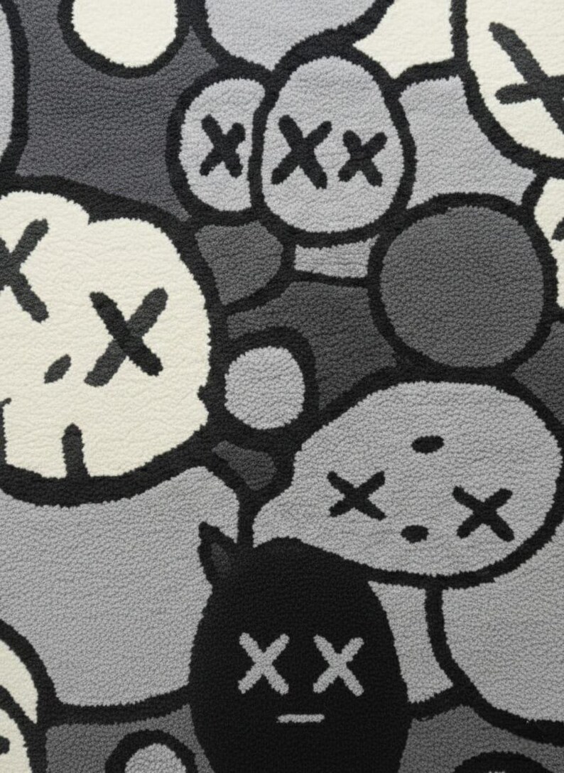 May include: Close-up of a rug with a repeating pattern of cartoon-like faces and shapes in shades of grey, black, and white. The design features stylized eyes and mouths, creating a playful and modern aesthetic.