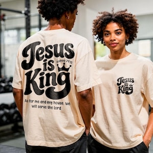 May include: Two people wearing cream-colored t-shirts with the text "Jesus is King" in black. The back of one shirt features the text "Jesus is King" with a crown and the Bible verse Joshua 24:15. The front of the other shirt has the same text and crown.